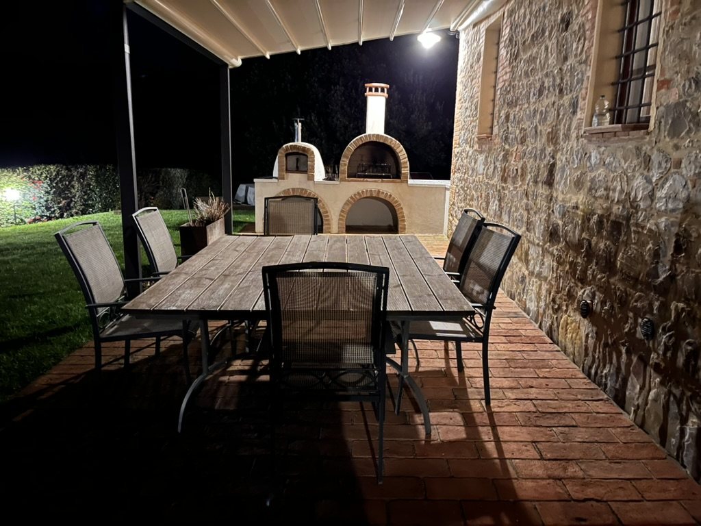 Covered terrace at night with the pizza oven